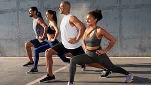 Group of people performing lunges outdoors, demonstrating effective exercise techniques for strength and fitness