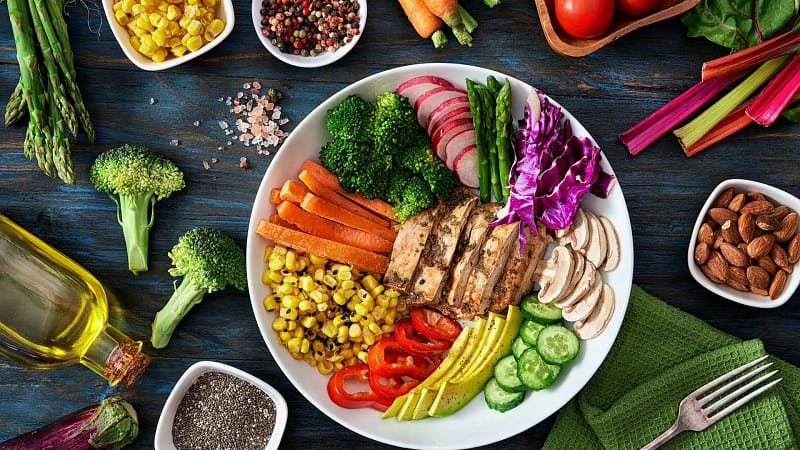 Colorful balanced diet plate with fresh vegetables, grilled tofu, avocado, and whole foods for healthy nutrition